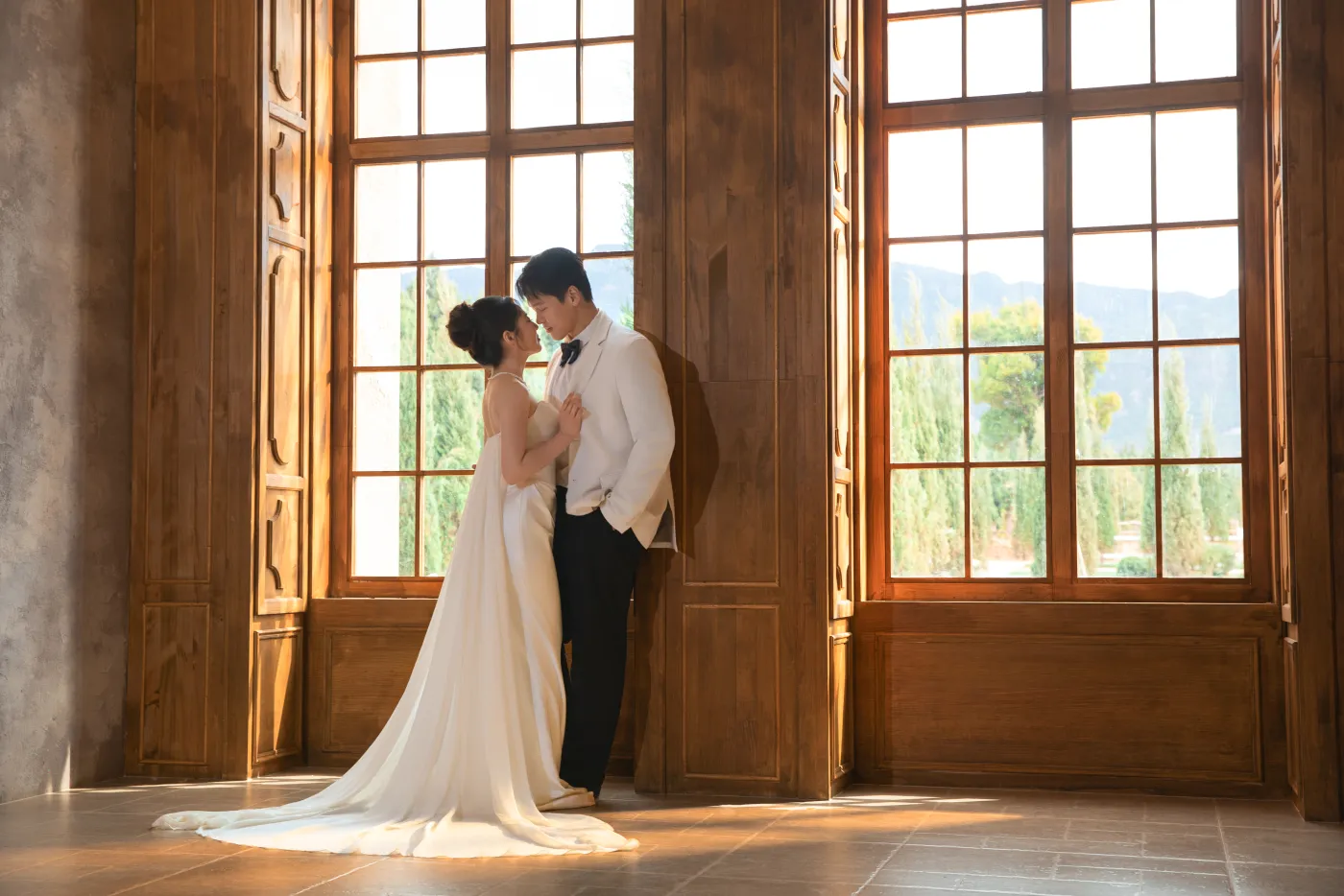 Gina and Han standing together beside warm wooden windows
